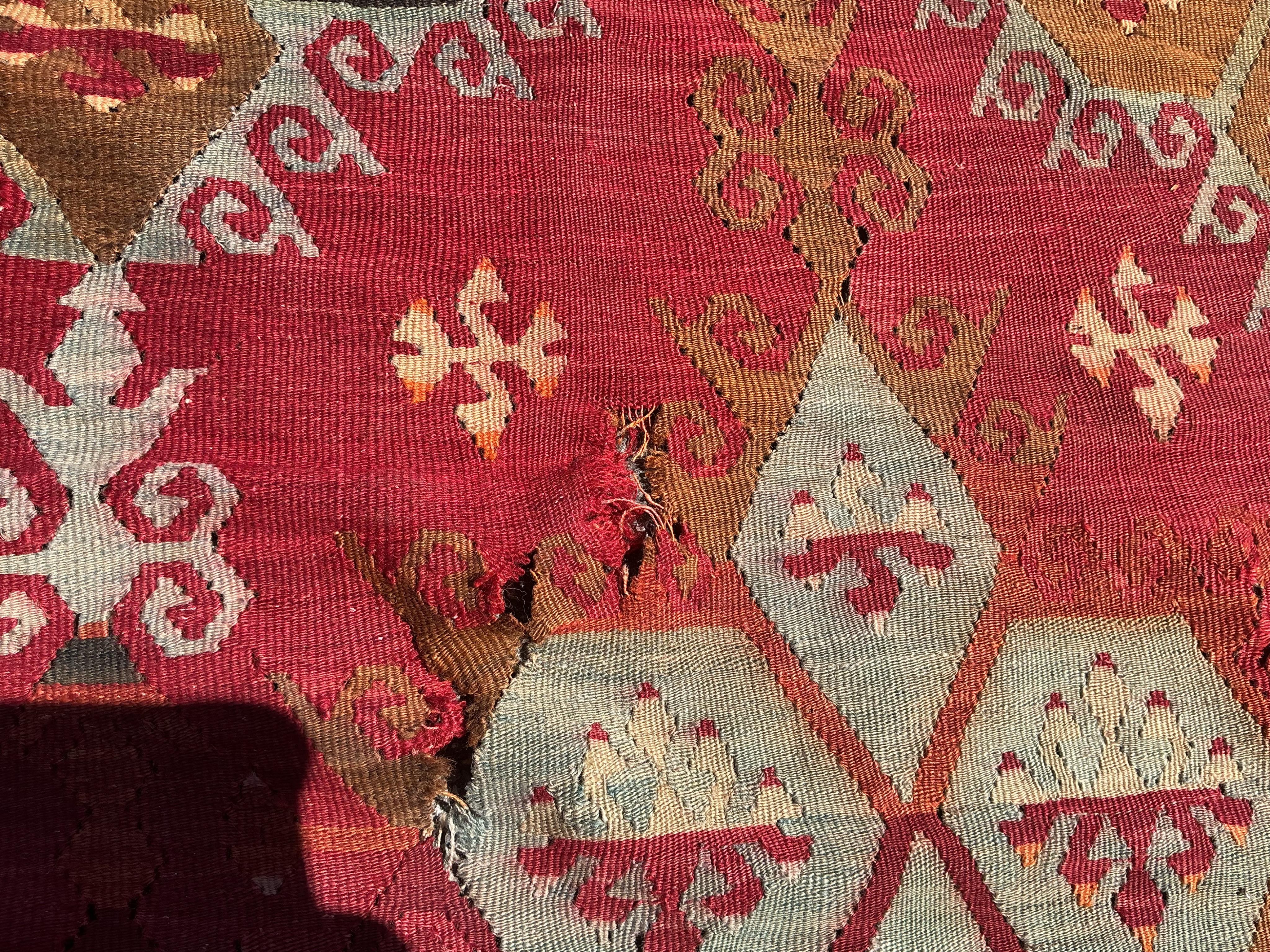 A Turkish Anatolian Kilim polychrome flatweave carpet, woven with geometric lozenges, on a pink field, 350 x 273cm